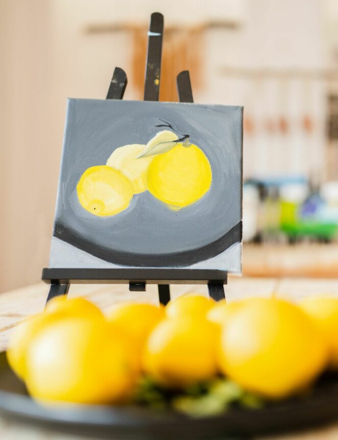 Painting of lemons done at the Artists Collective, sitting next to a plate of lemons