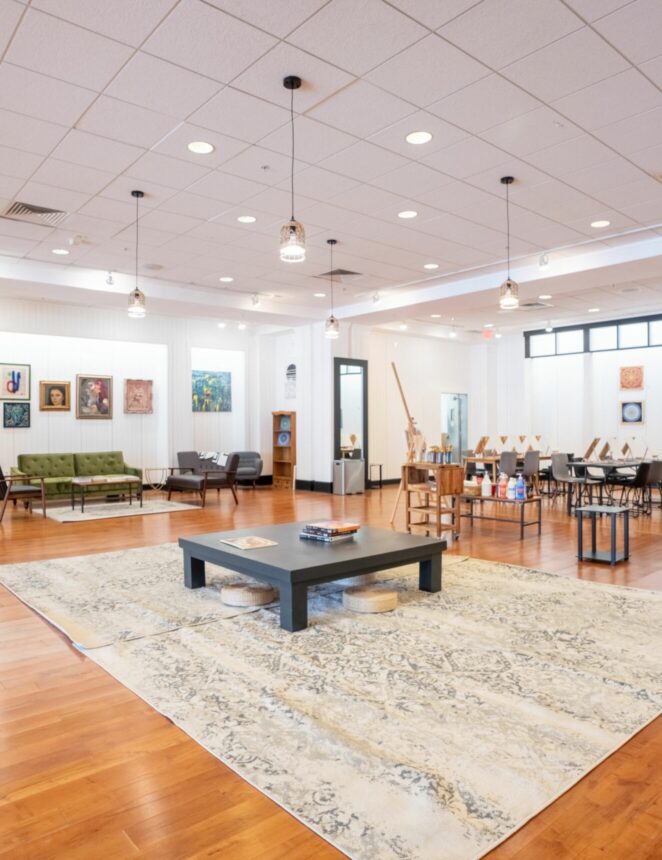 inside the Artists Collective. An open floor with tables and local artists' work hanging on the wall.