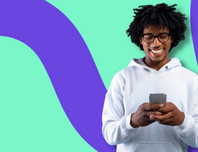 A young African American man holds a cell phone and smiles in front of a teal background with a purple accent wave practicing effective social media copywriting.
