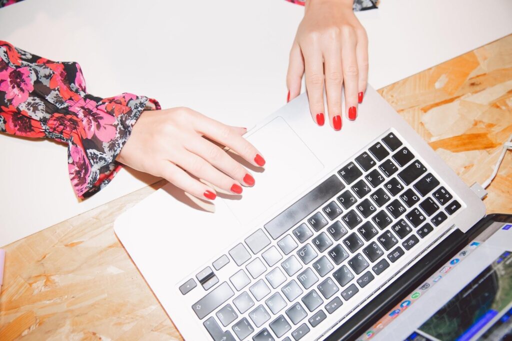 overhead picture of a woman with red fingernails beauty blog writing on laptop