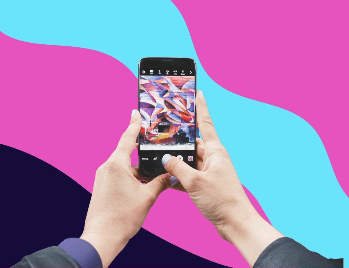 Hands holding phone to take photo for Instagram in front of colorful swirly background in post about business captions for Instagram