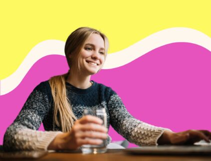woman in a sweater smiling and typing on a laptop in front of colorful swirling background for post about content seo writers