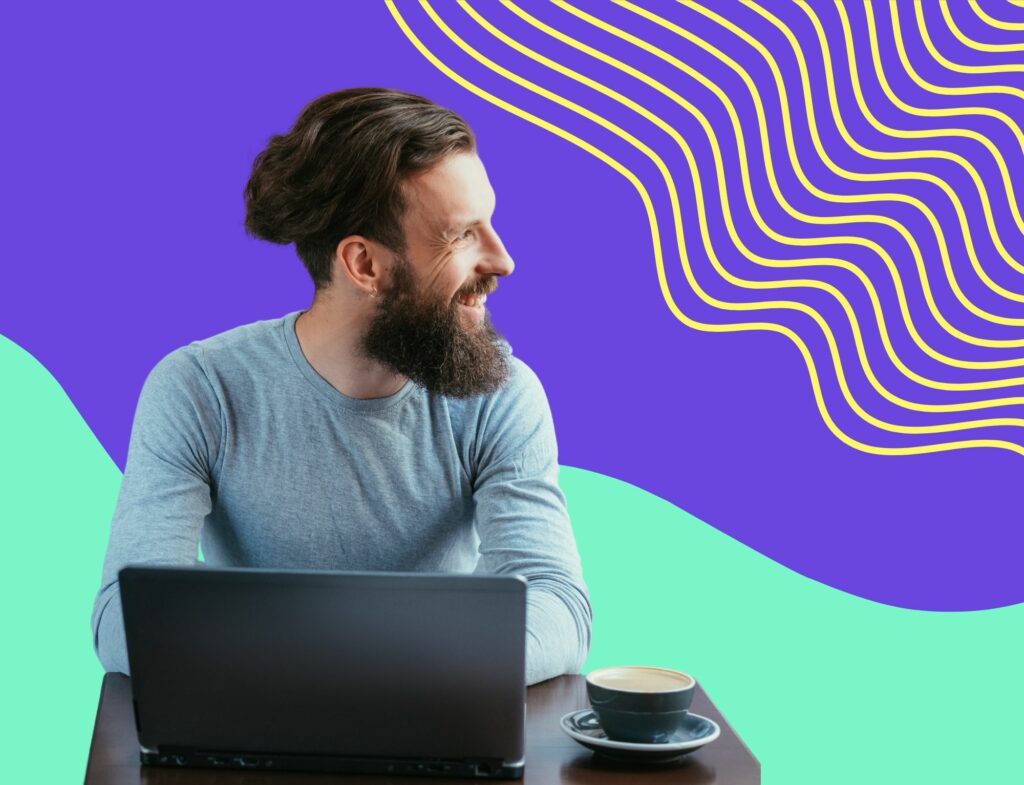 millennial man writing website content and smiling in front of swirling colorful background