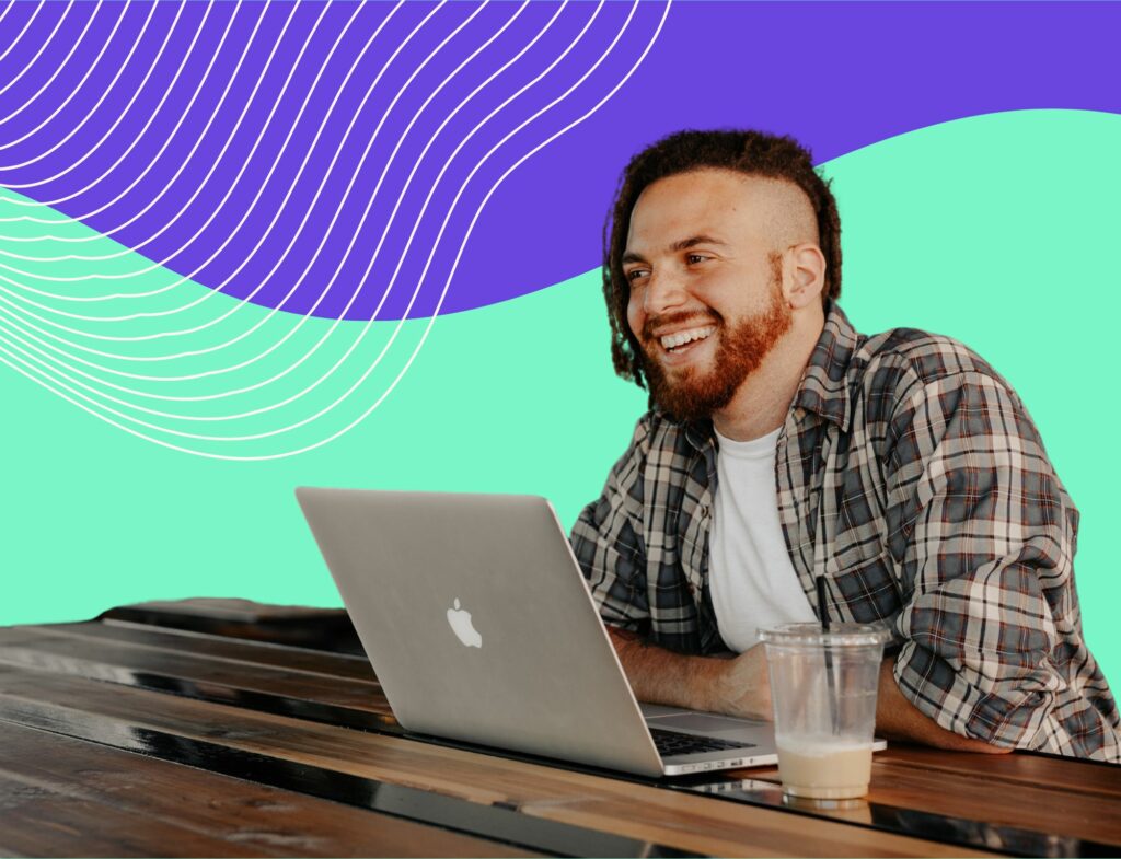 smiling man working on laptop in front of colorful background for post about brand voice and tone