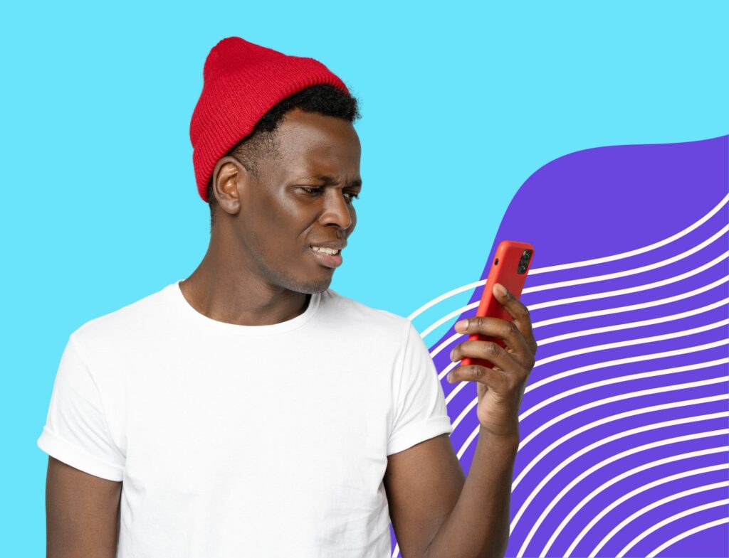 man in beanie looking at phone confused and disapproving in front of blue background