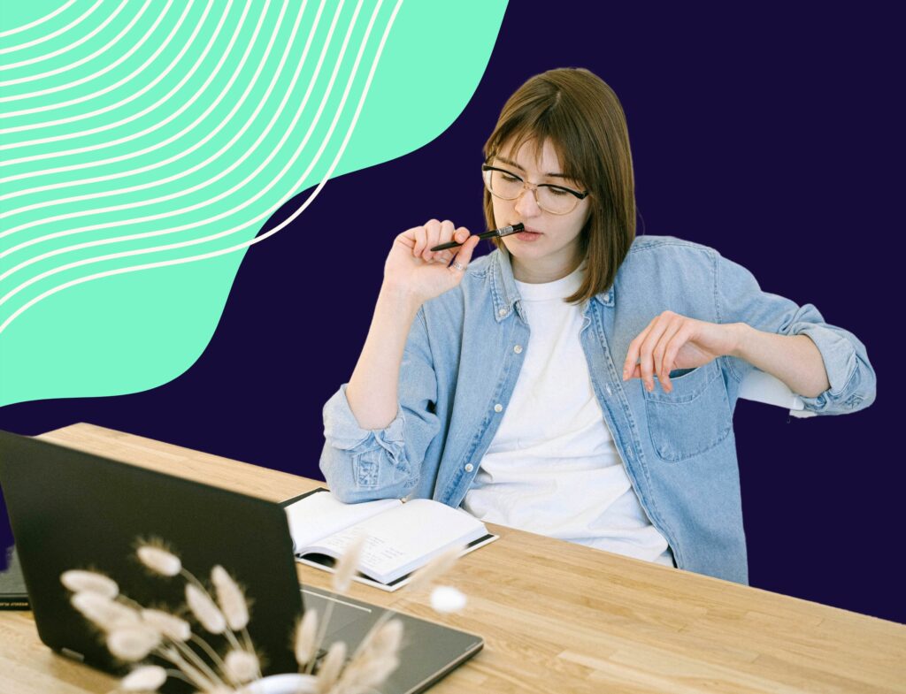 woman sitting at desk thinking with pen in her mouth