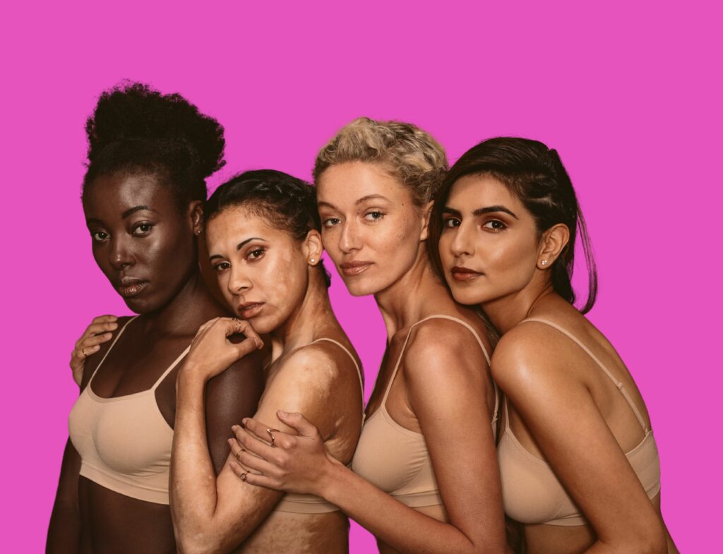 group of four diverse models posing in front of pink background
