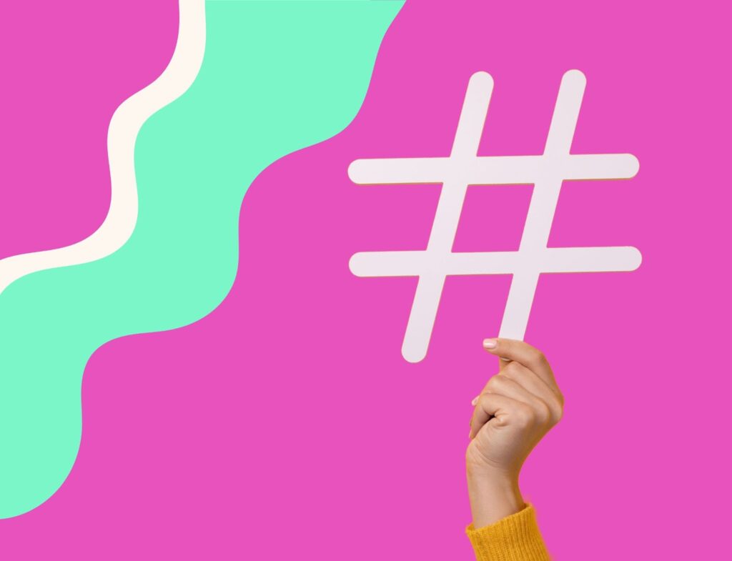 hand holding a hashtag symbol in front of pink and green swirling background