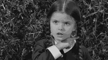 Gif of black and white Wednesday Addams making throat cutting motion