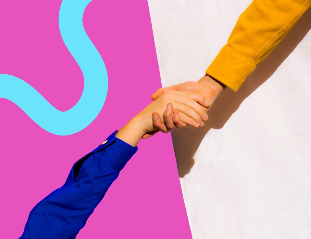 One hand pulling up another hand in front of pink background with blue squiggle