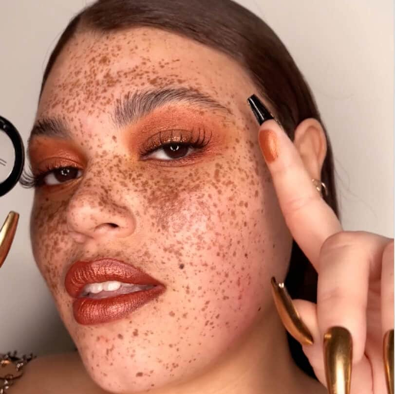 Freckled model wearing copper makeup look