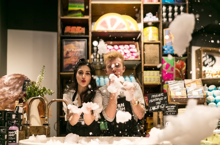 Two Lush employees at a Lush retail store blowing bubbles into the camera